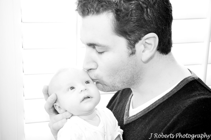 B&W of baby being kissed by father - baby portrait photography sydney